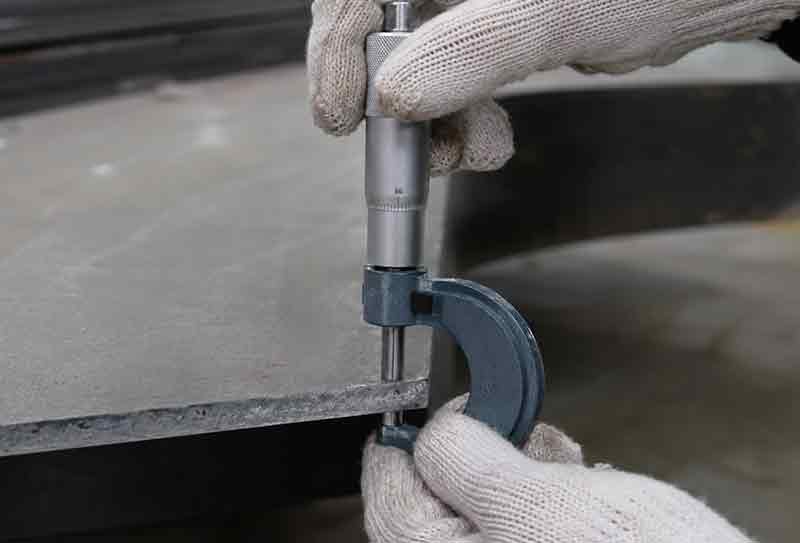 工人使用测厚工具对310S钢板或中厚板进行厚度检测